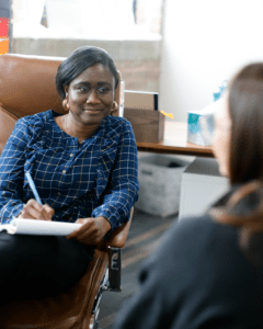 Woman writing in notebook in therapy office